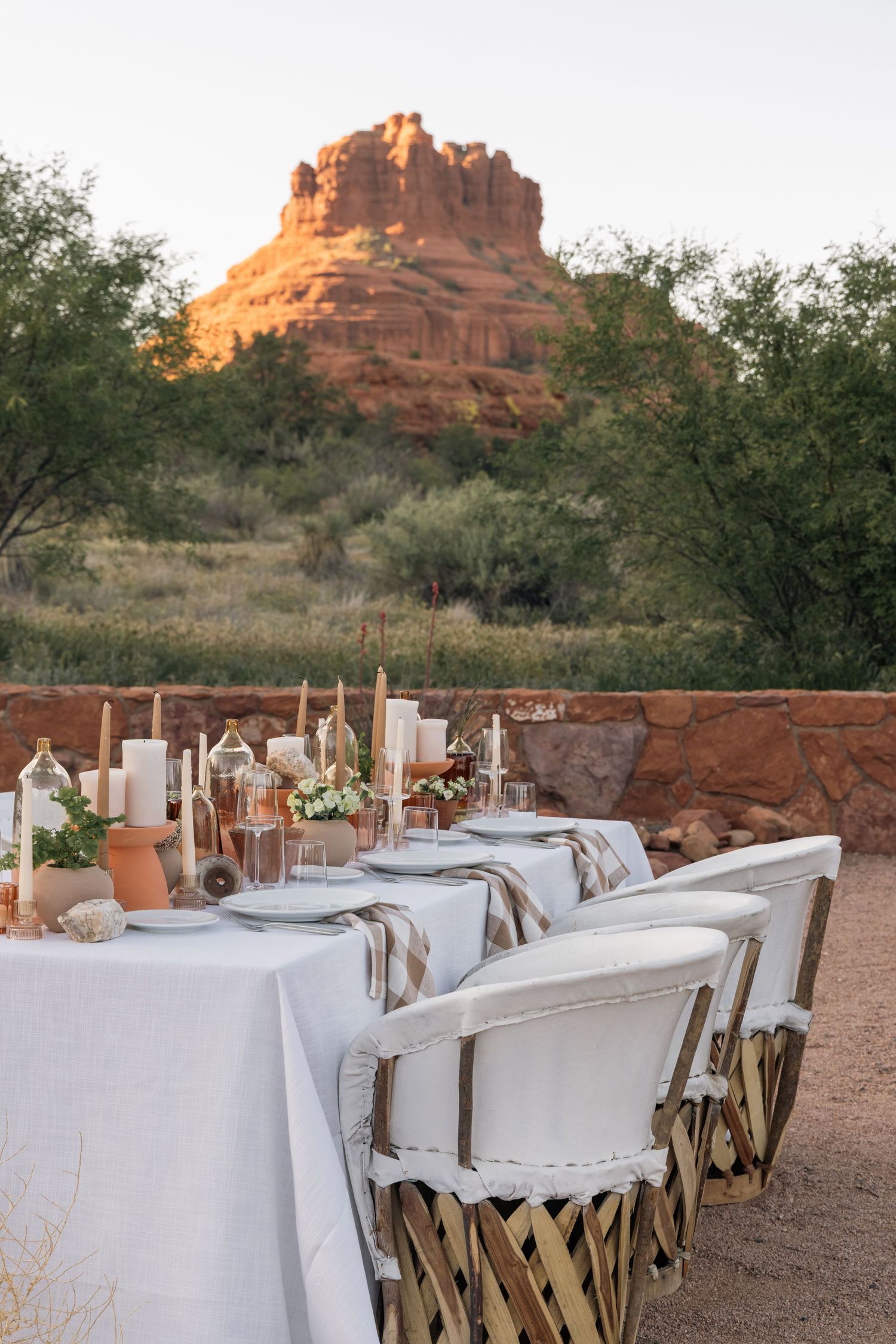 Elegant outdoor table setting with white linens and desert views of Bell Rock in Sedona at golden hour.