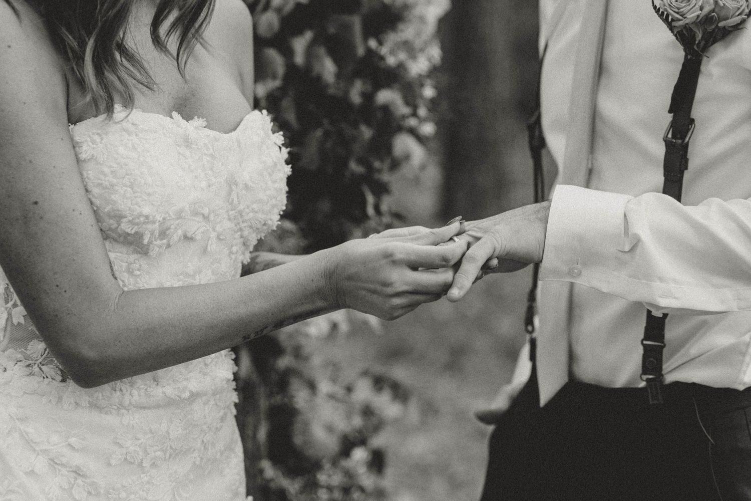 Black and white photo showing hands exchanging wedding rings during ceremony.