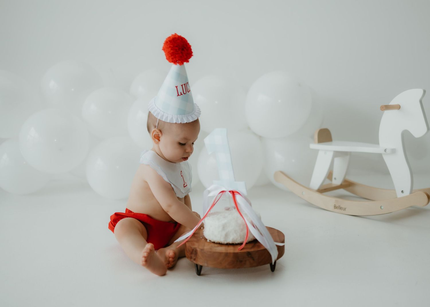 A collection of sweet, minimalist baby portraits in white tones featuring a rocking horse and red accents. Dallas/fort-worth photographer.