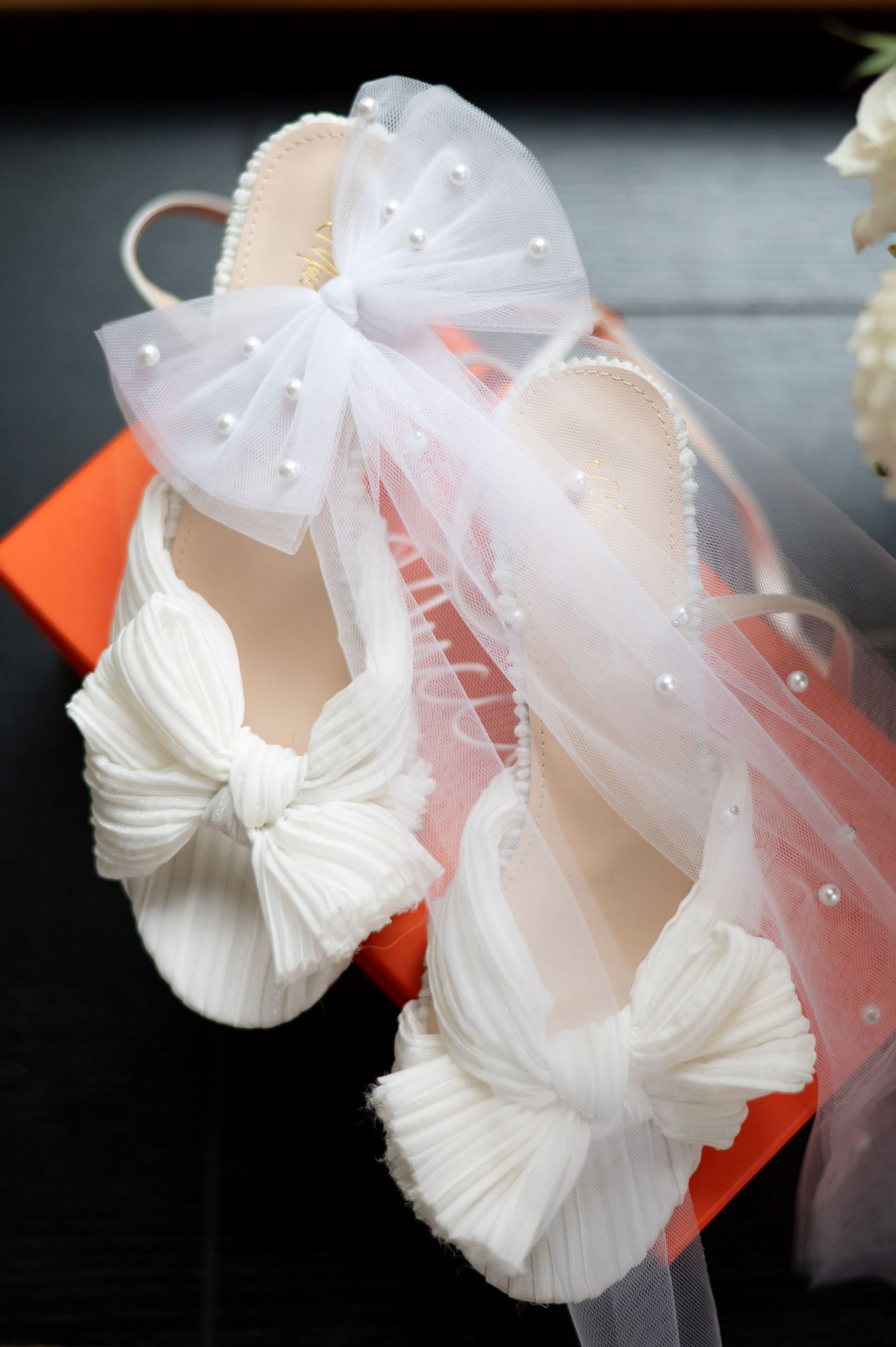 White tulle bow hair accessories with delicate pearl beads shown from different angles on orange tags.