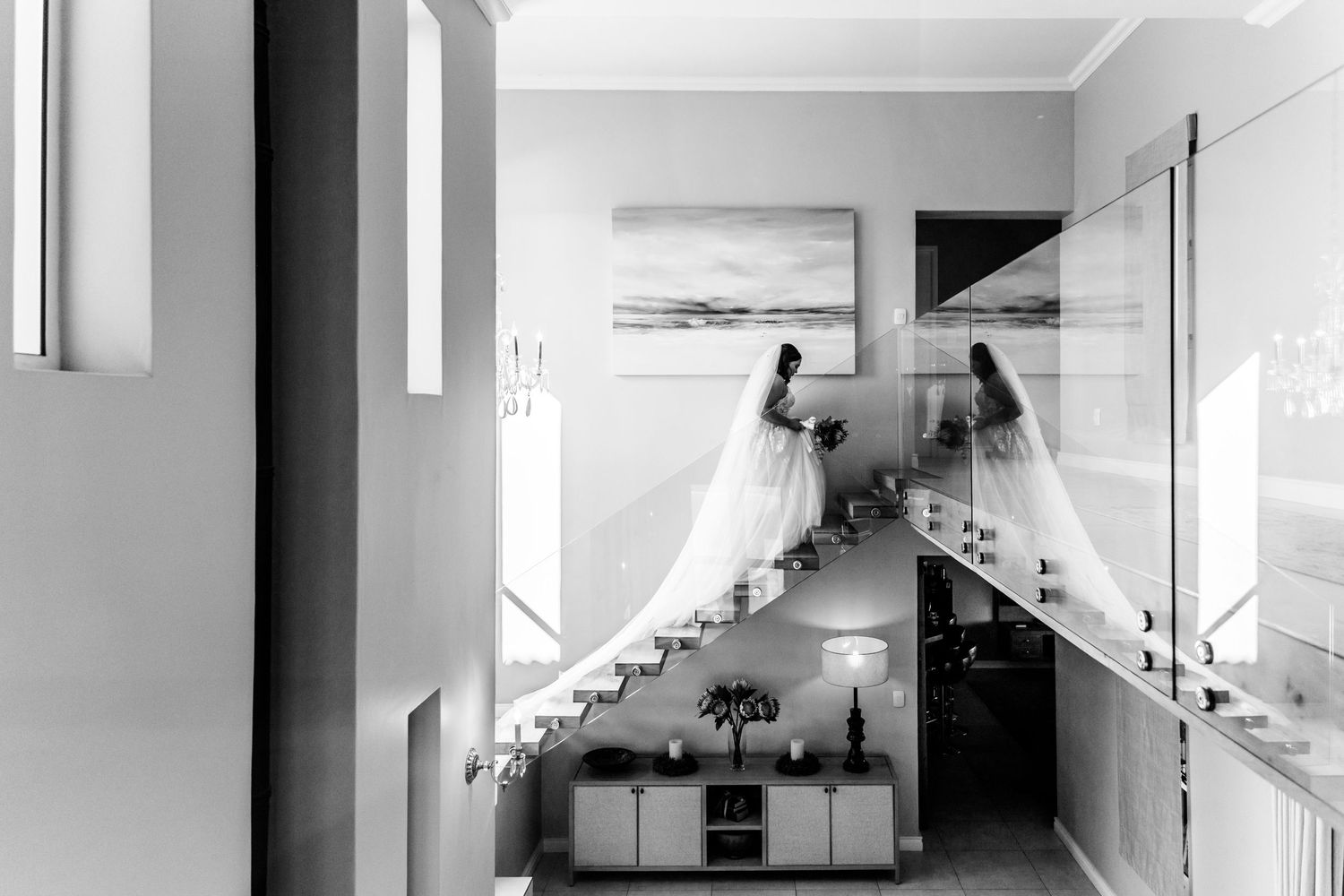High-angle view of a minimalist monochrome interior hallway with stairs and built-in storage features.