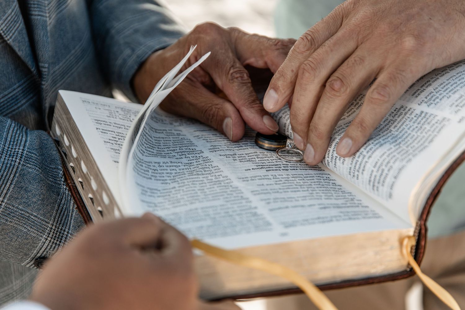 Person in denim reads a Bible with hands resting on the open pages, showing a contemplative study moment.