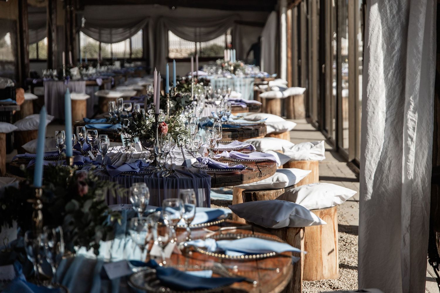An elegant table setting with wine glasses and place settings displayed in a long row at an upscale restaurant venue.