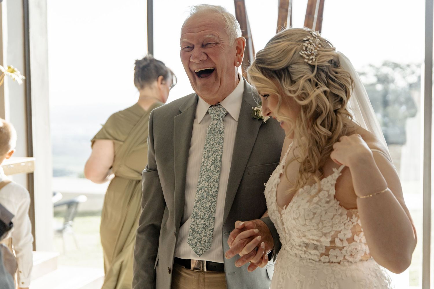 Wedding guests share joyful laughter together during an indoor reception celebration.