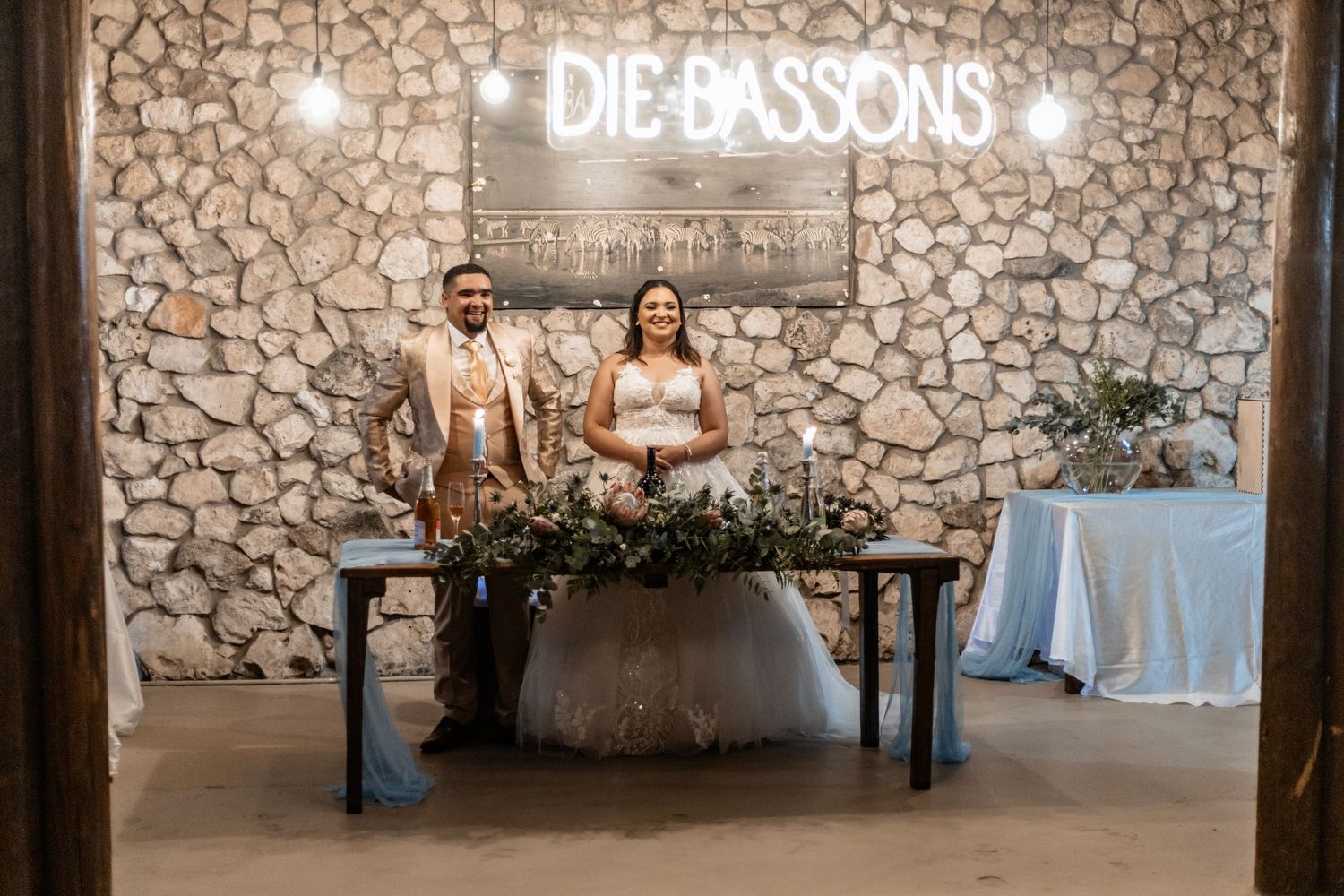 Wedding couple sits at rustic stone venue with green garland adorned table and dreamy evening lighting at DeCasons venue.