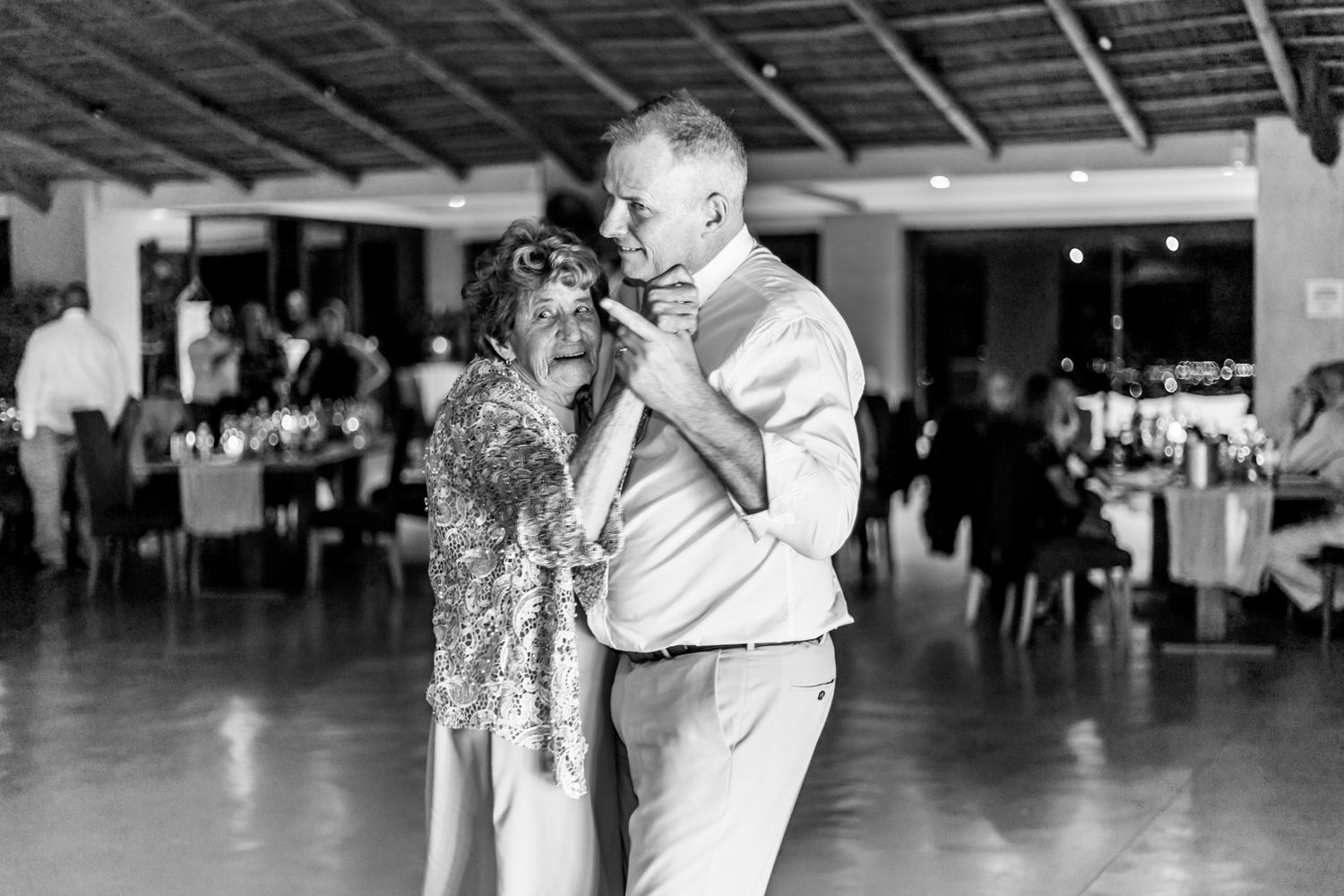 A couple shares a romantic dance together at a wedding reception in black and white photography.
