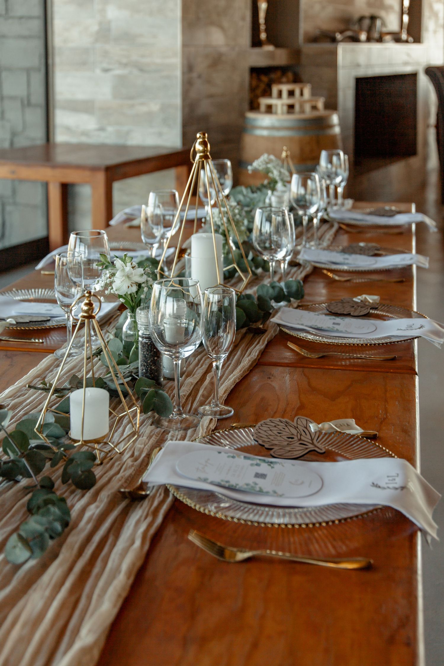 Elegant wedding table setting with glass plates, eucalyptus garland and candles on wooden rustic table.