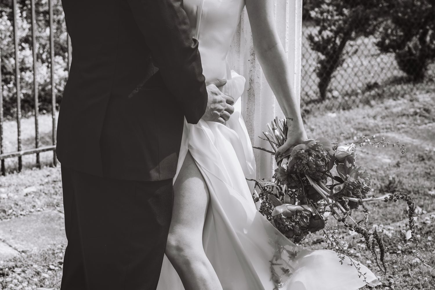 A black and white wedding photo showing a close-up of a bride in a white dress and groom in a suit standing outdoors. Bleak House Tennessee