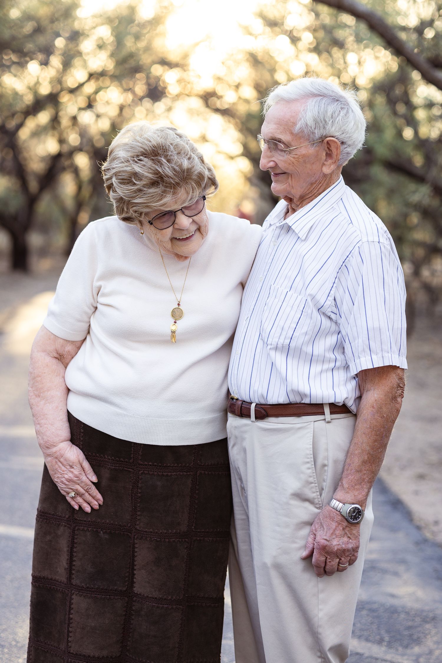 An elderly couple shares a tender moment while standing together outdoors.