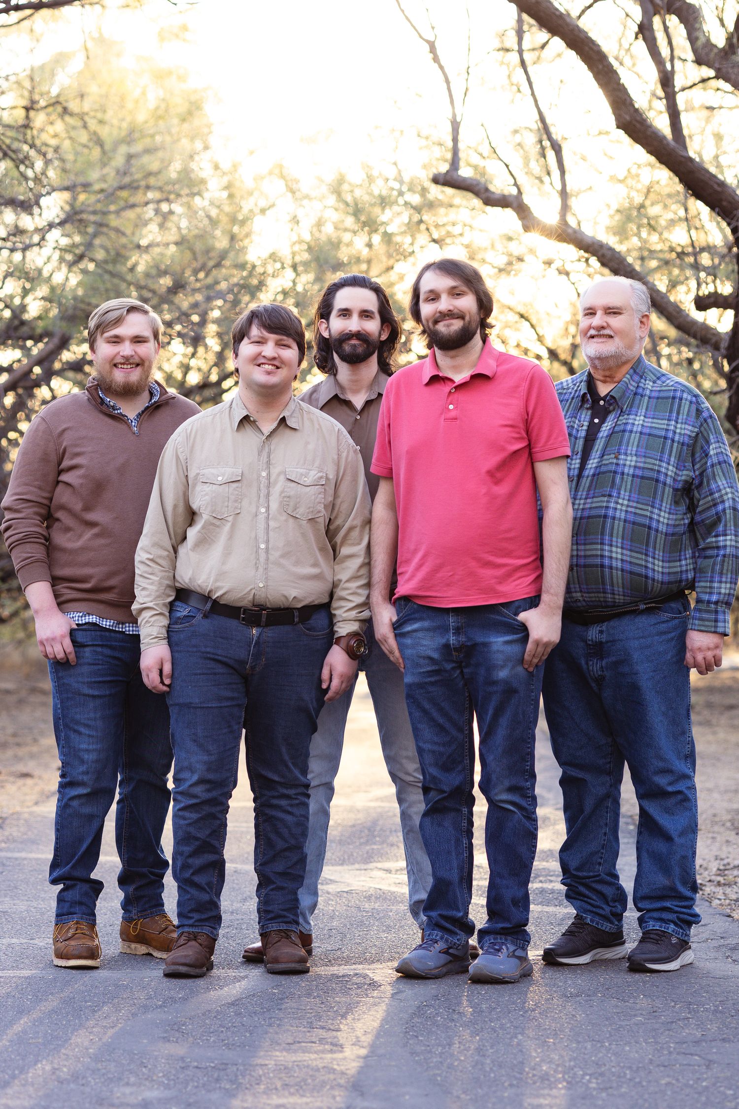 Group of five people standing together outdoors wearing casual clothing.
