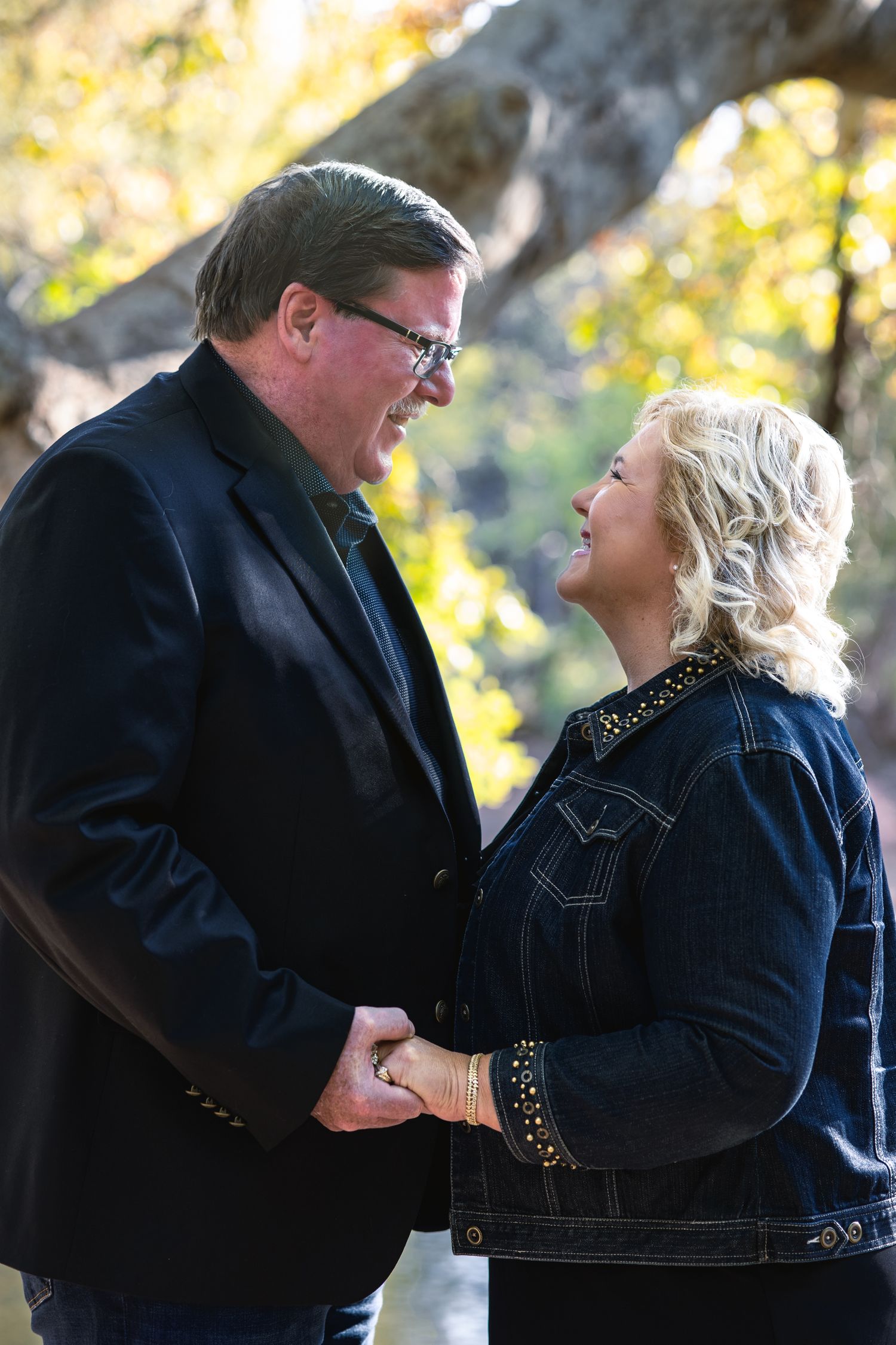Couple shares an intimate moment while holding hands outdoors on a sunny day.