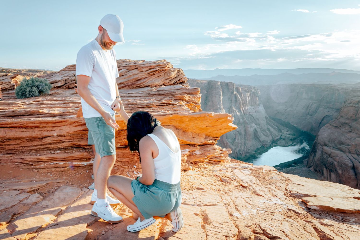 A couple shares a moment on the edge of a scenic canyon overlook with turquoise river below. Surprise Proposal