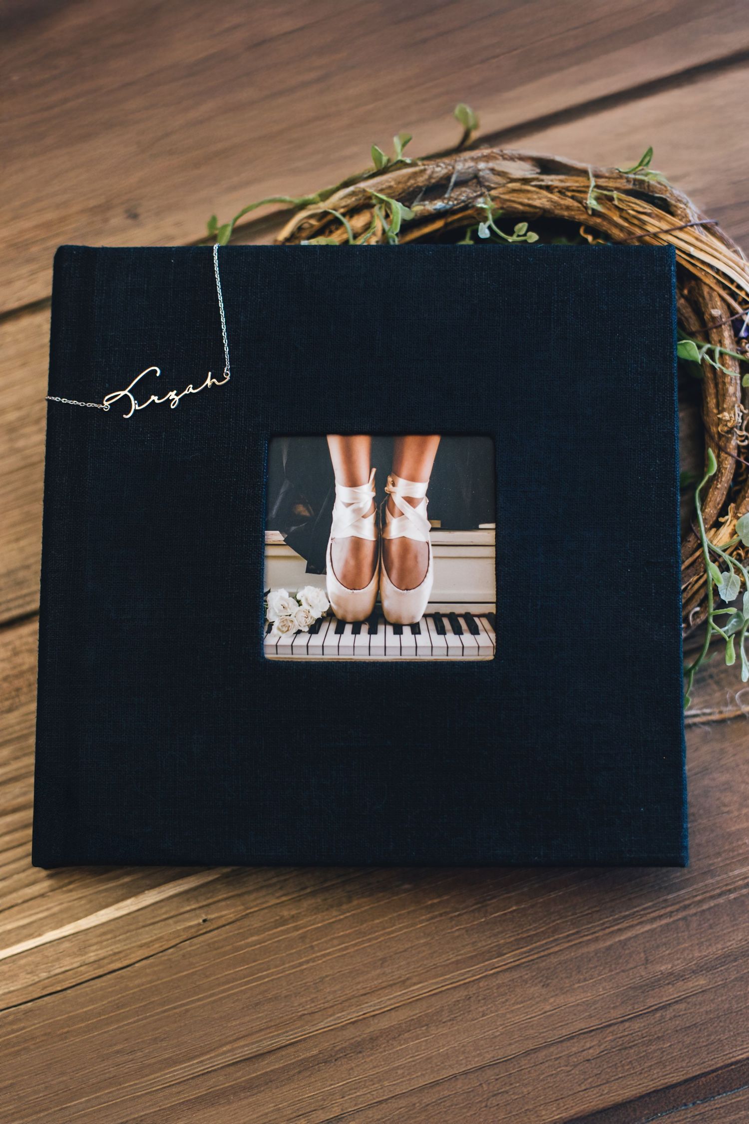 A series of five black books or albums arranged on a wooden surface with piano-themed details visible.