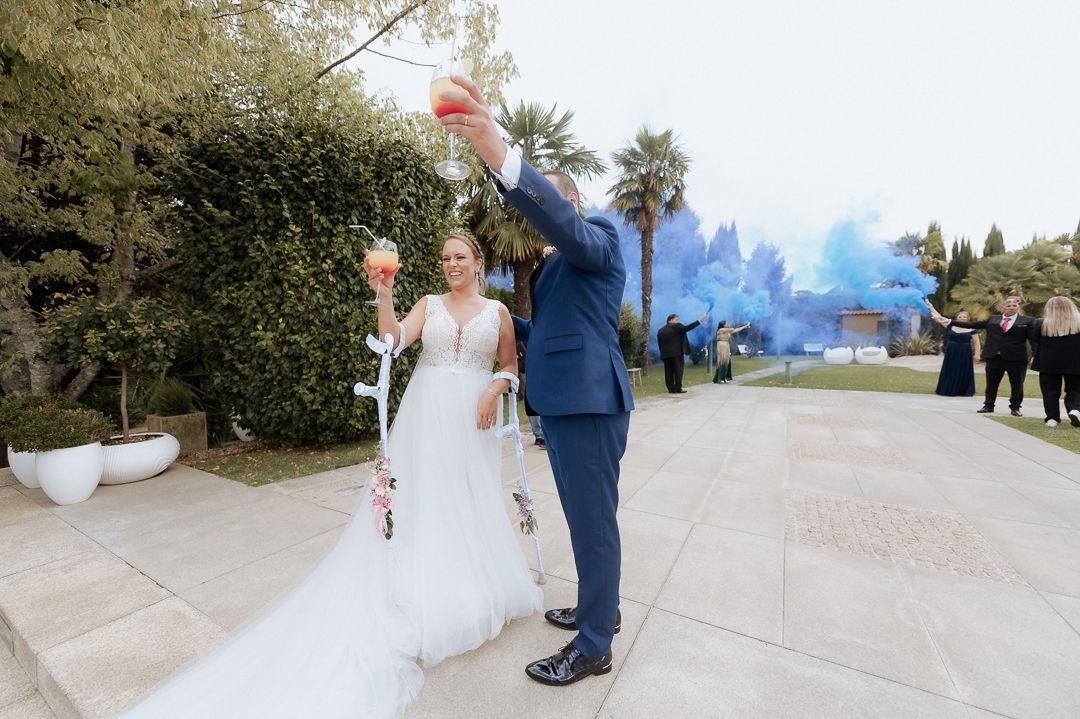 A couple celebrates at their wedding ceremony with blue smoke effects creating an ethereal atmosphere in the background.