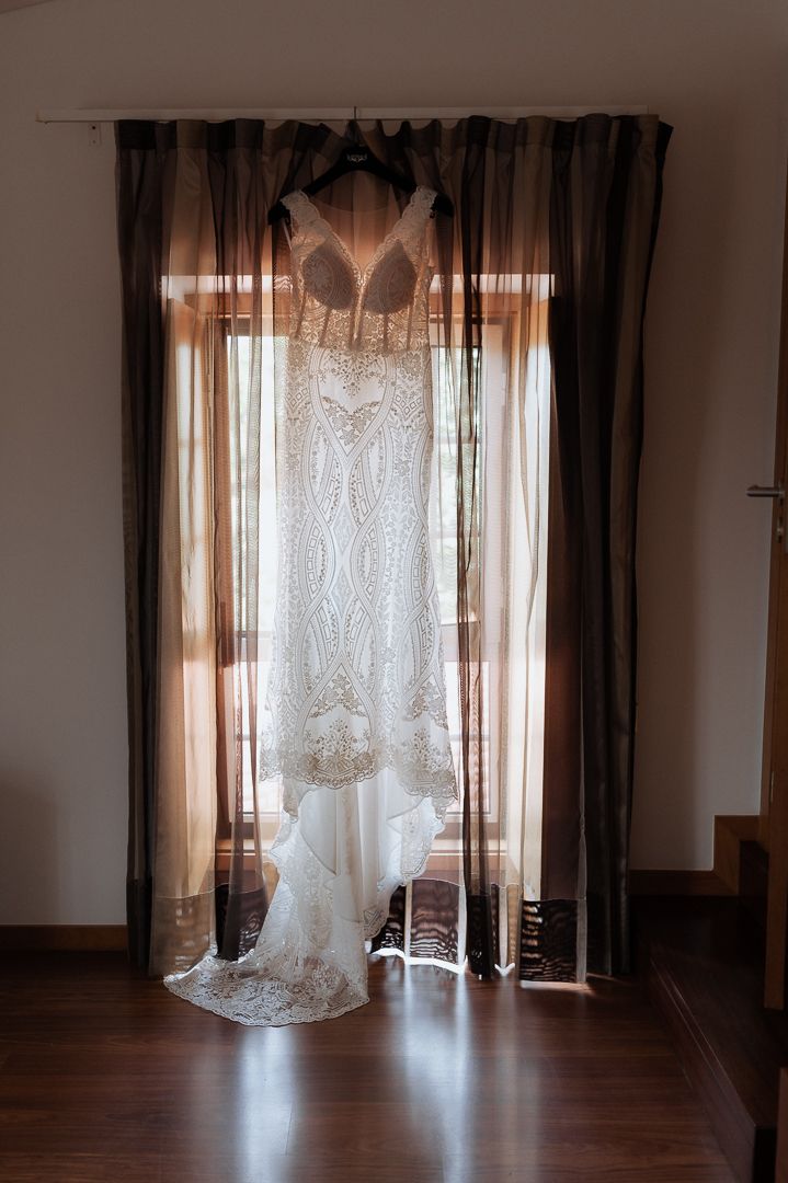 Bright sunlight filters through sheer white and brown curtains in an empty room with wooden floors.