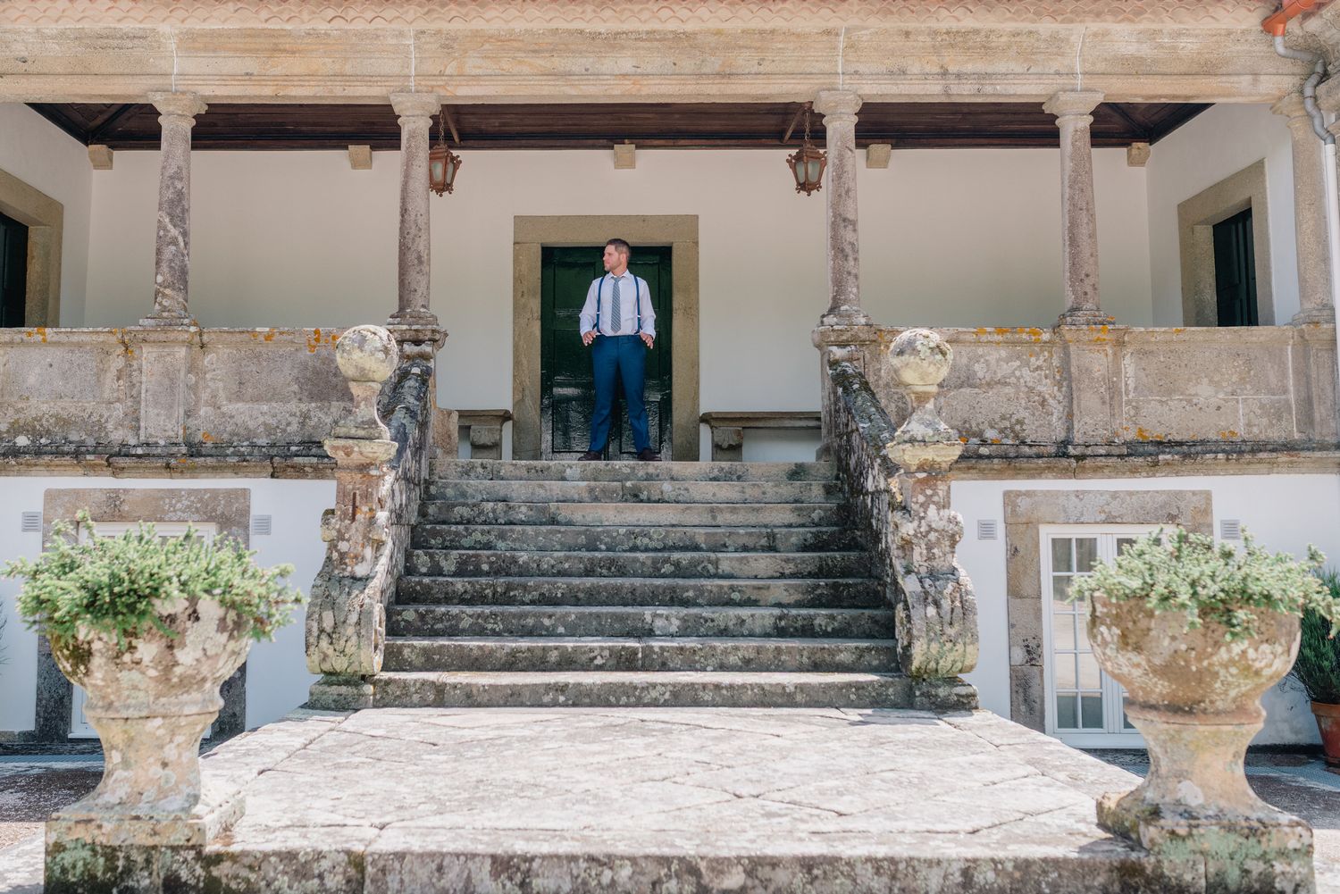 Entrada histórica da vila de pedra com escadaria ornamentada e vasos decorativos.