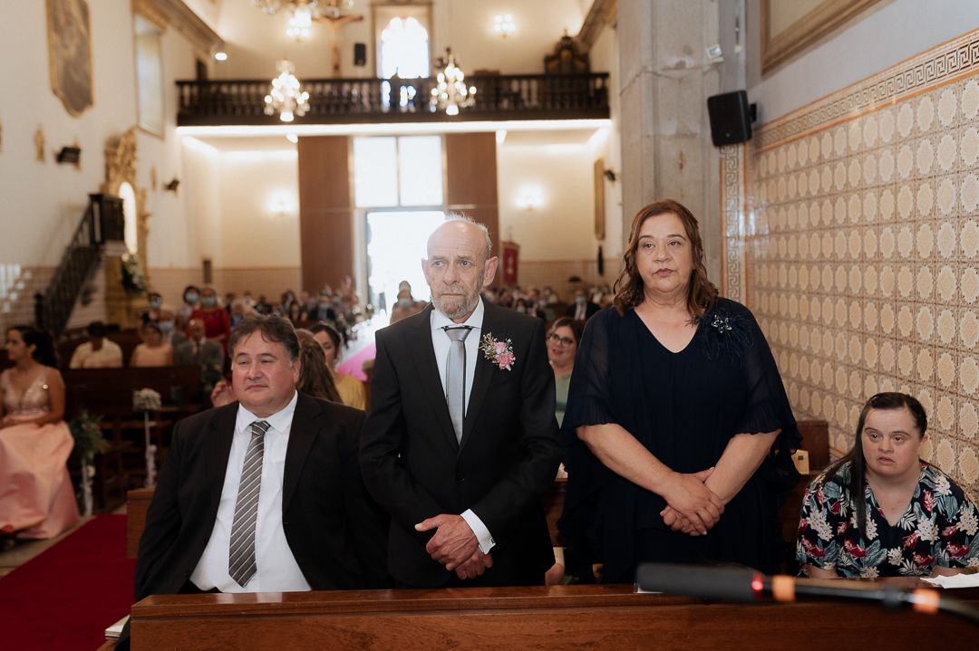 People standing together in a traditional church interior with ornate walls and a chandelier during a formal ceremony.