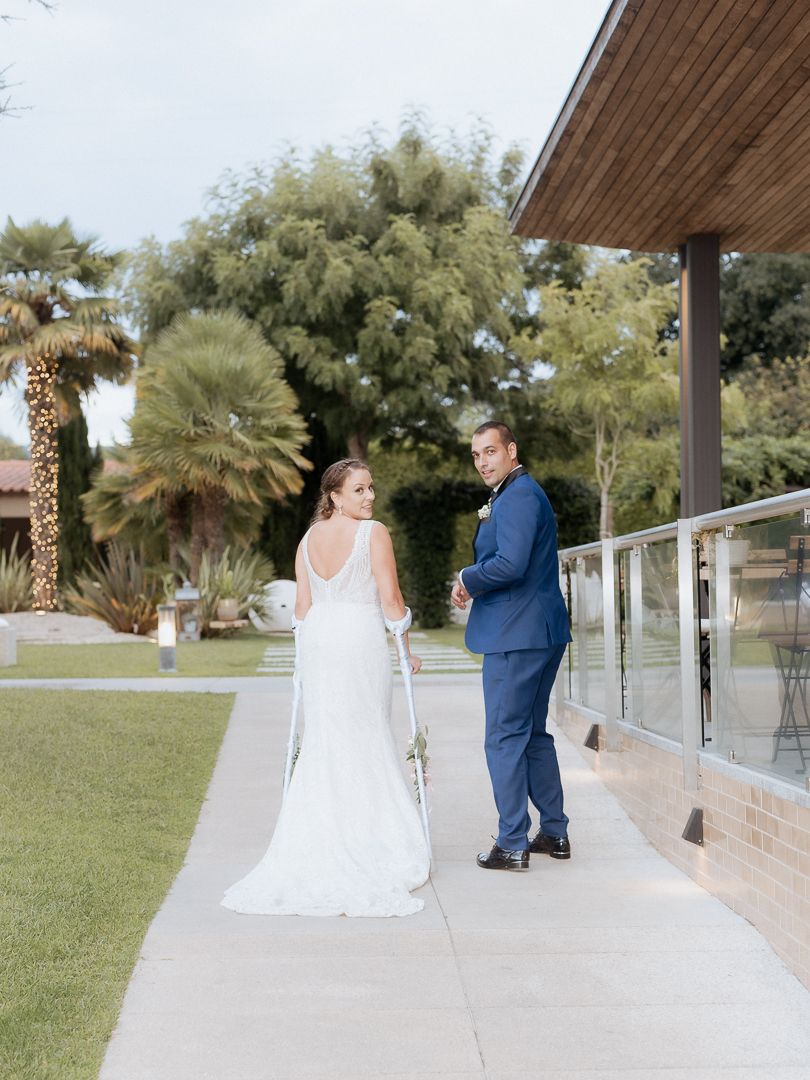 A couple shares a tender moment on a patio with palm trees and greenery in the background.
