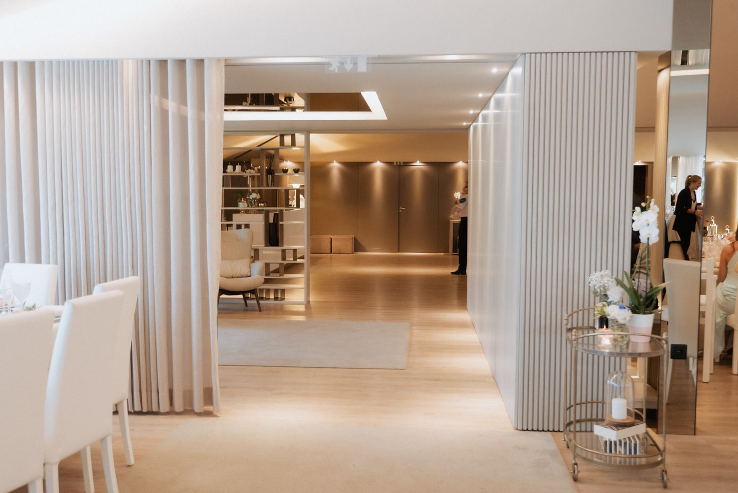 Modern luxury spa interior with white curtains, sleek columns and warm lighting creating an elegant minimalist atmosphere.
