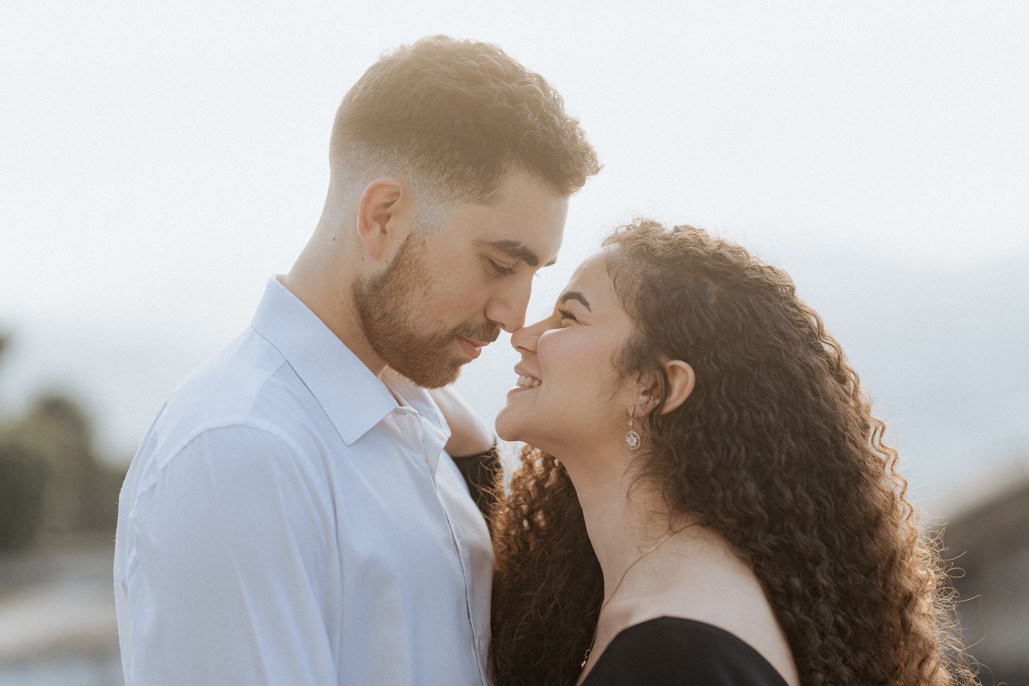 Um casal romântico compartilhando um momento íntimo ao pôr do sol sob suave iluminação natural ao ar livre. Sessão de solteiros em Braga.