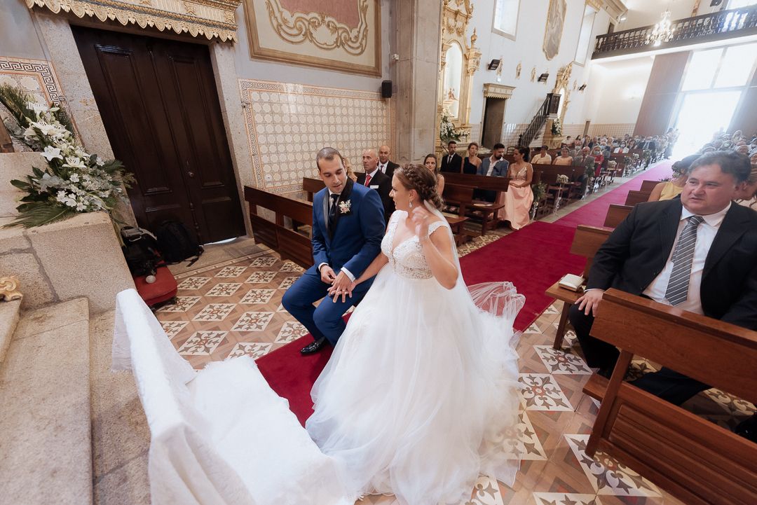 A wedding ceremony in a beautifully decorated church with ornate tiled floors and wooden pews.