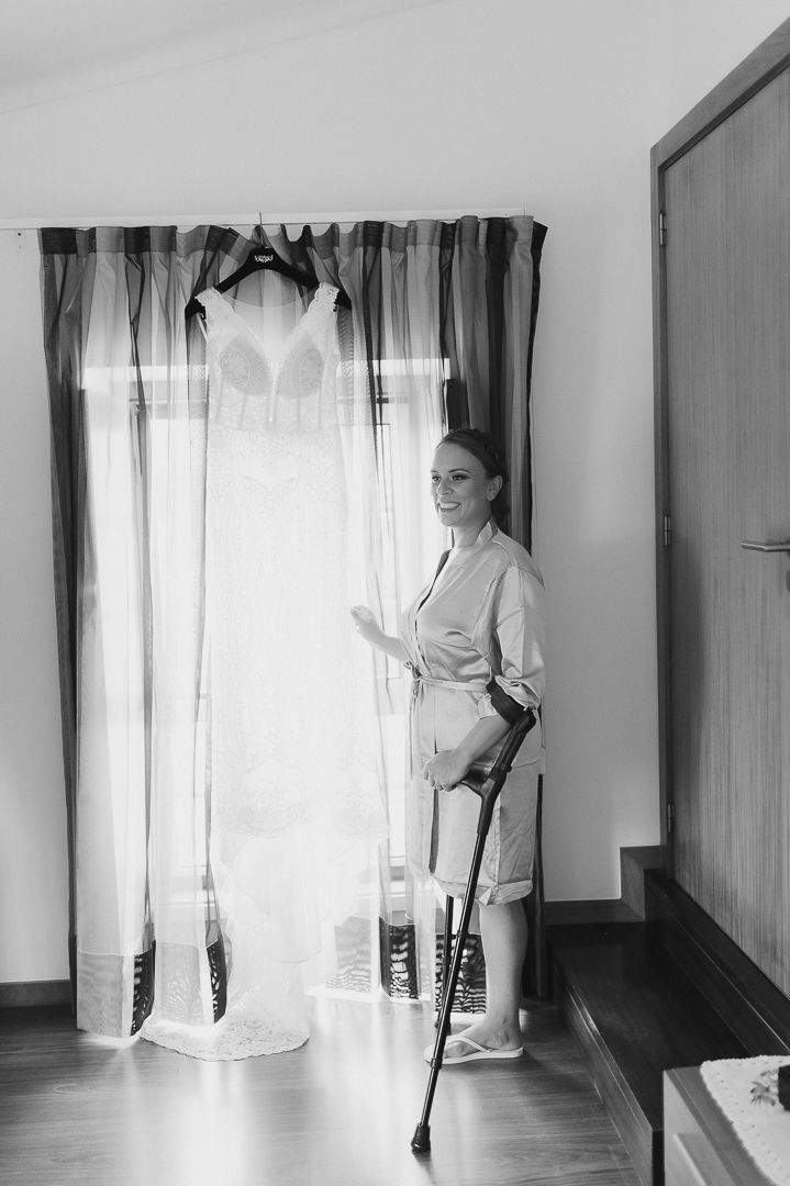 A classic black and white photo showing someone standing by sheer curtains in a sun-lit room wearing light colored attire.