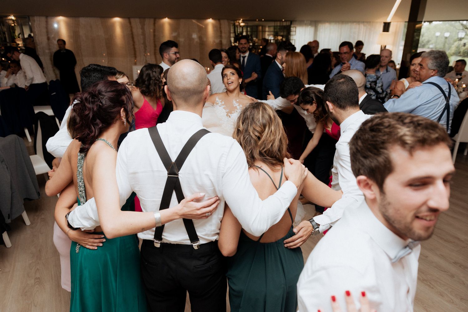 Wedding guests dance together on the dance floor while wearing coordinated emerald green dresses and formal attire.