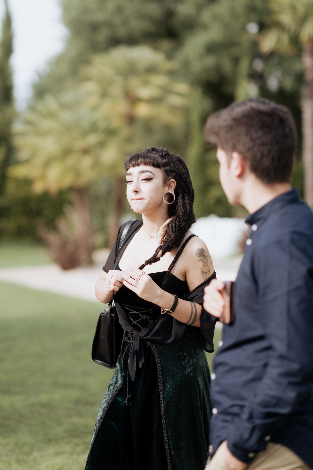 Two people having a conversation outdoors in formal attire, with one wearing a velvet black dress.