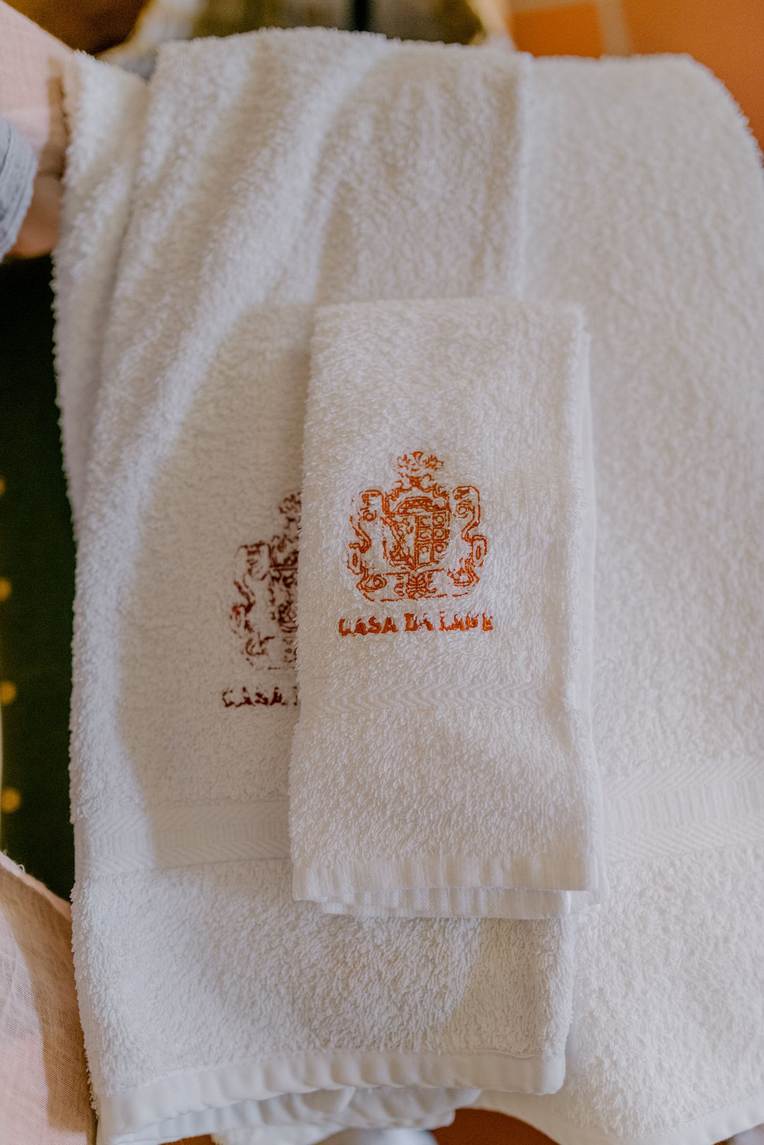 Toalhas de hotel brancas luxuosas com logotipo da Casa Da Laura bordado em linha marrom.