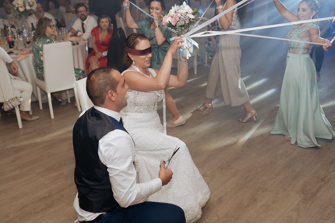 Newlyweds play a fun game during their reception as guests cheer them on at an indoor wedding venue.