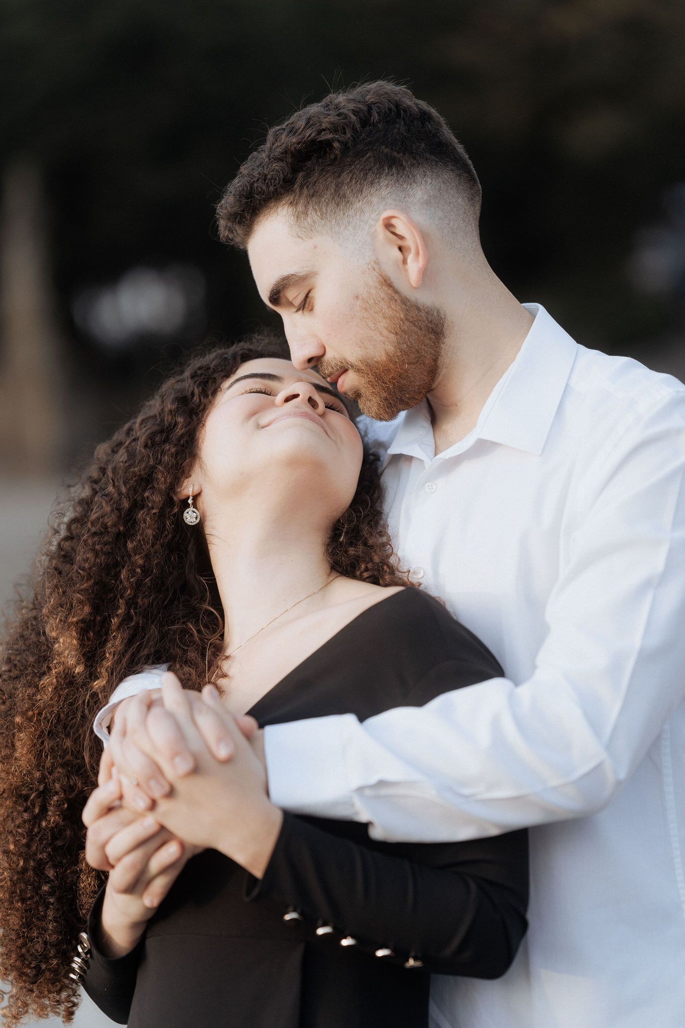 Casal se abraçando em um momento romântico e íntimo, tendo como pano de fundo um ambiente externo desfocado. Sessão de namoro em Braga.