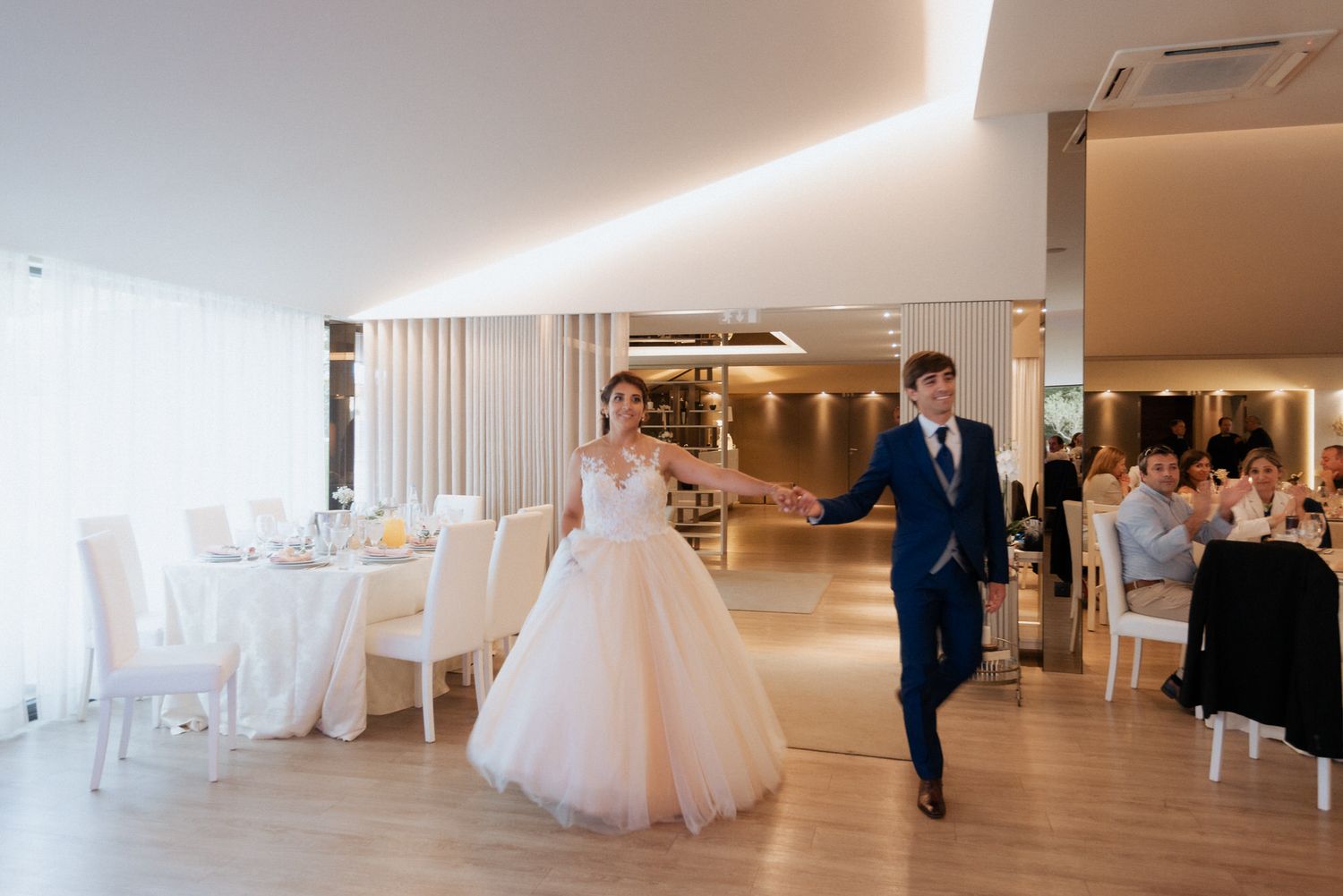 Panoramic view of a bright white modern wedding venue interior with hardwood floors and decorative white drapery.