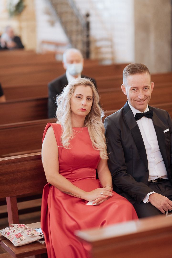 Wedding guests seated in wooden church pews during a formal ceremony.