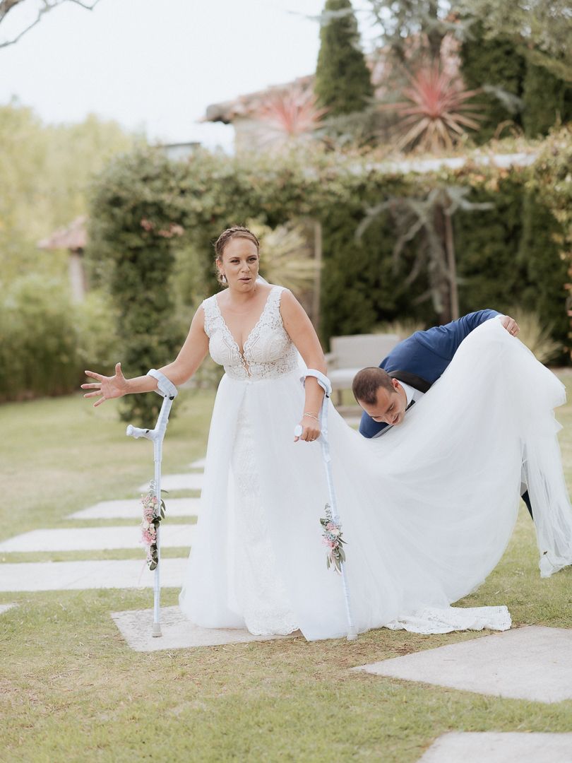 A whimsical wedding moment on a garden path with a flowing white dress against a lush green backdrop.