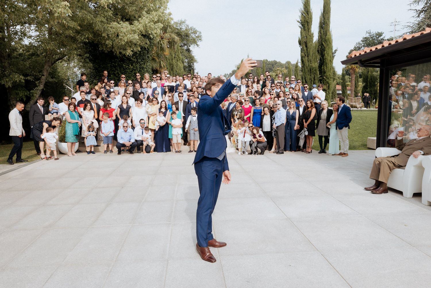 Wedding guests gather along the pathway outside a mediterranean style venue while couple shares their first kiss.