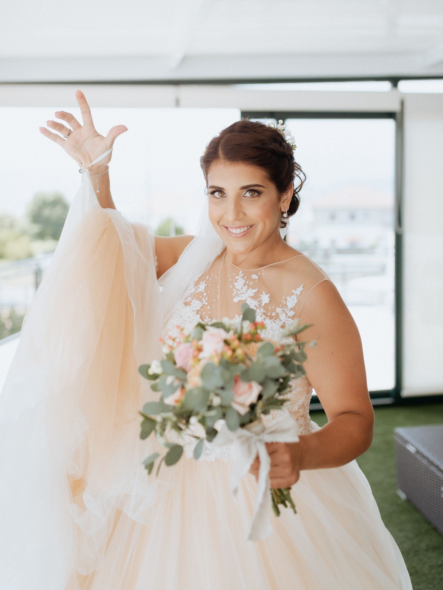 A bride in a flowing white wedding dress holds her bouquet while showing off playful dance moves.