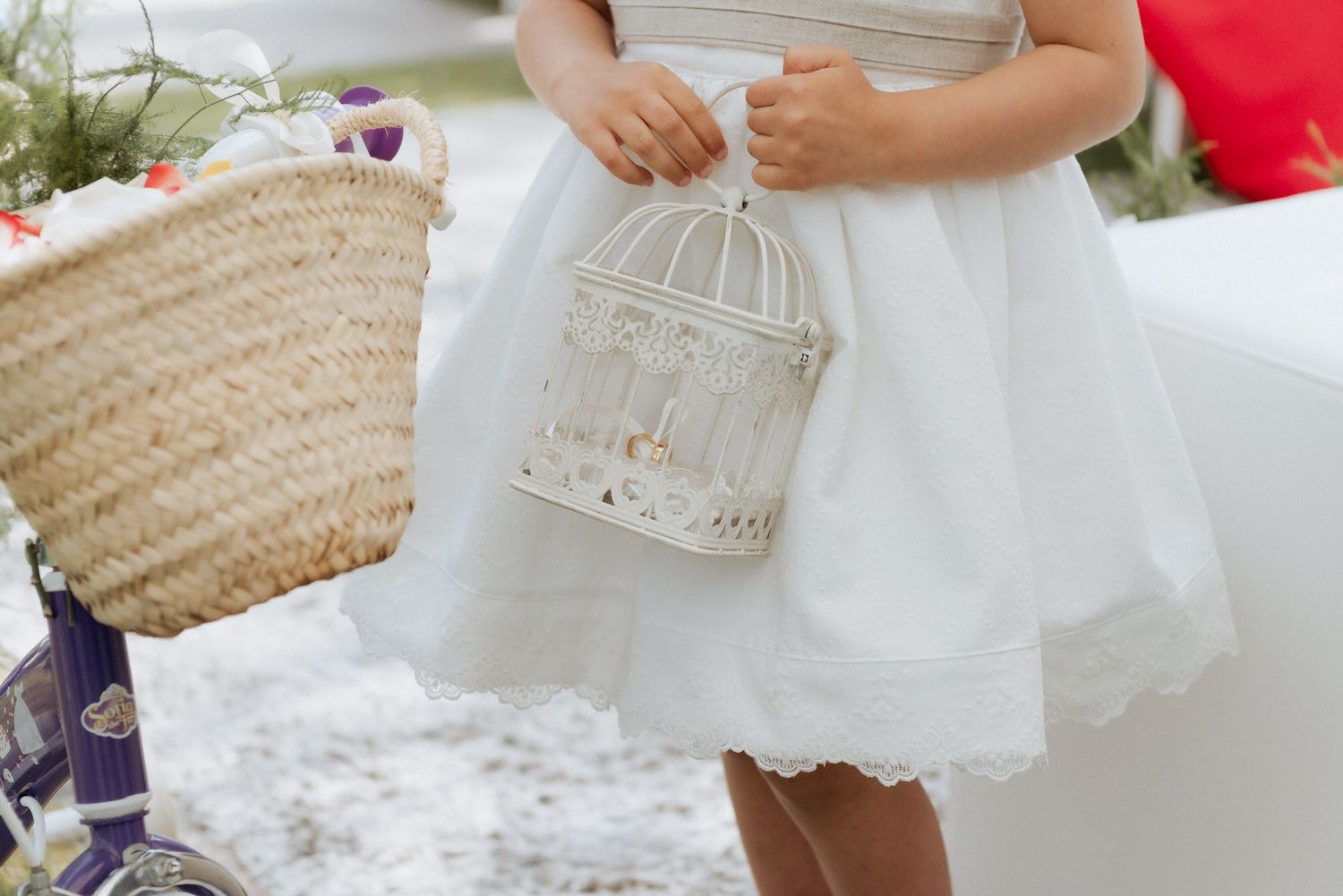 A closeup view of flowing white lace and fabric details from a dress against a light background.