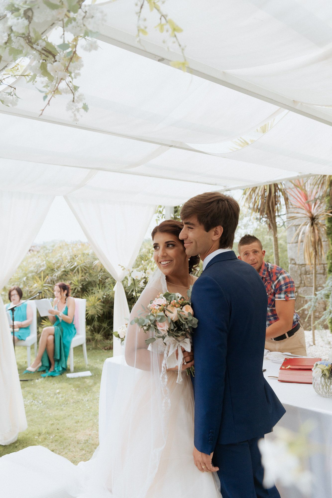 Happy couple shares a romantic first dance moment under white tent decorations at an outdoor wedding reception.