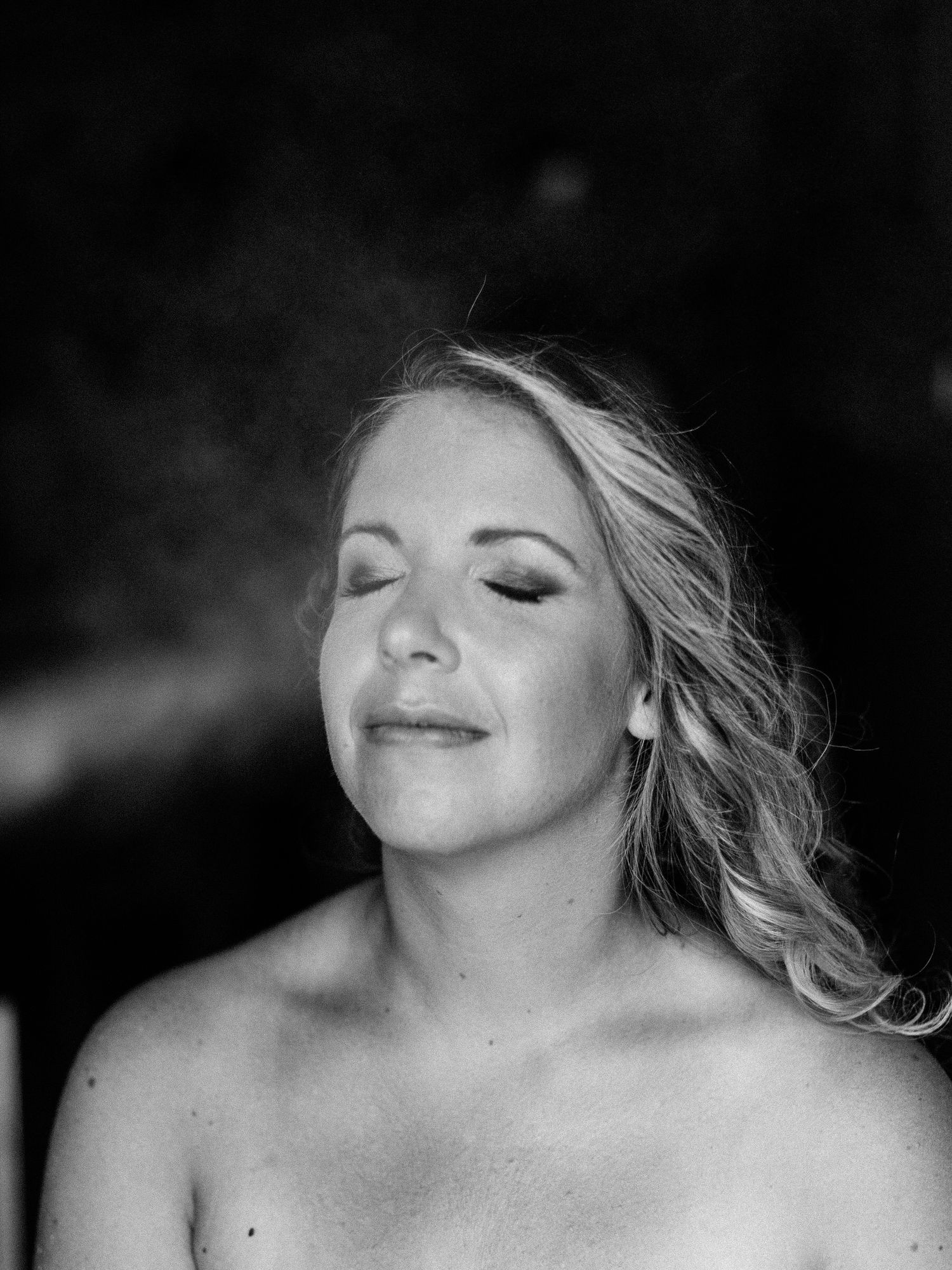 Retrato em preto e branco da noiva Nathalie com olhos fechados e cabelos soltos, com uma expressão serena.
