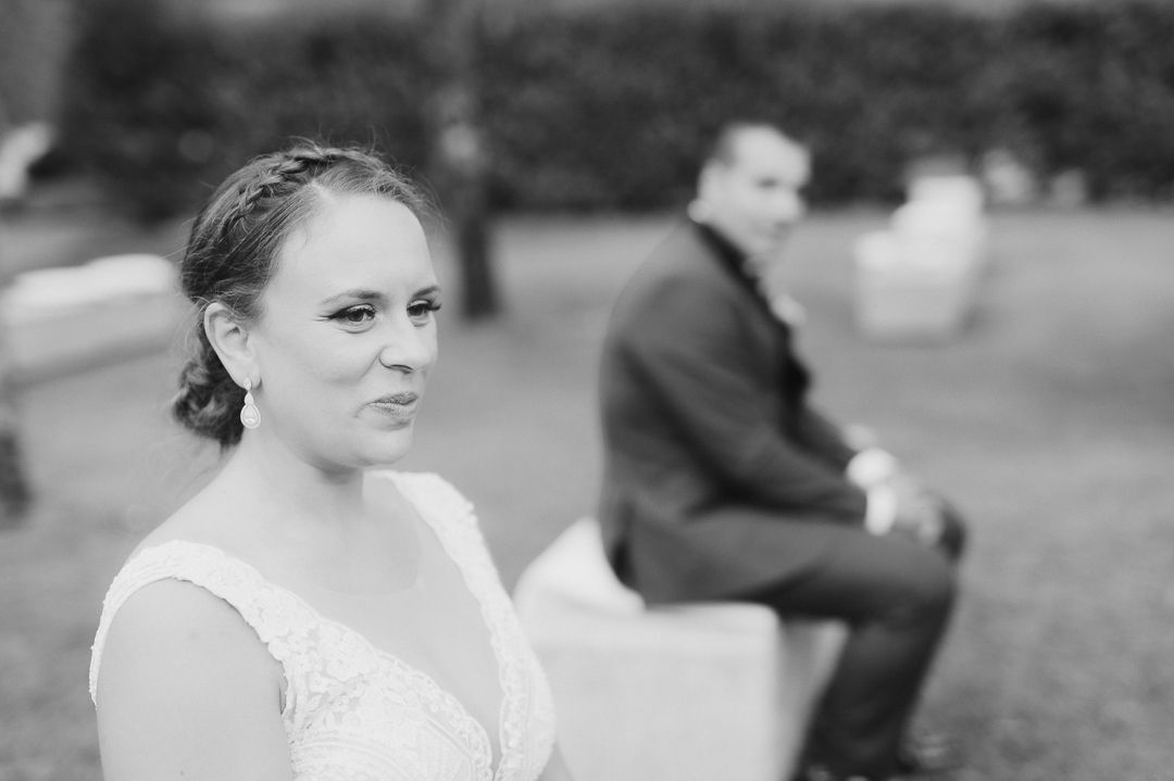 Elegant wedding photo composition with bride in foreground and groom sitting in background, shown in black and white.