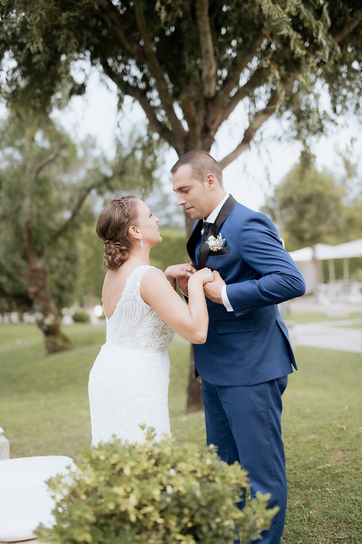 A couple shares a romantic dance outdoors under a large tree during their wedding celebration in a garden setting.