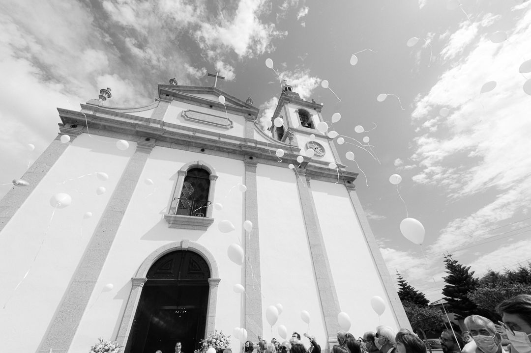 Exterior view of a white church facade with baroque architecture against a dramatic cloudy sky.