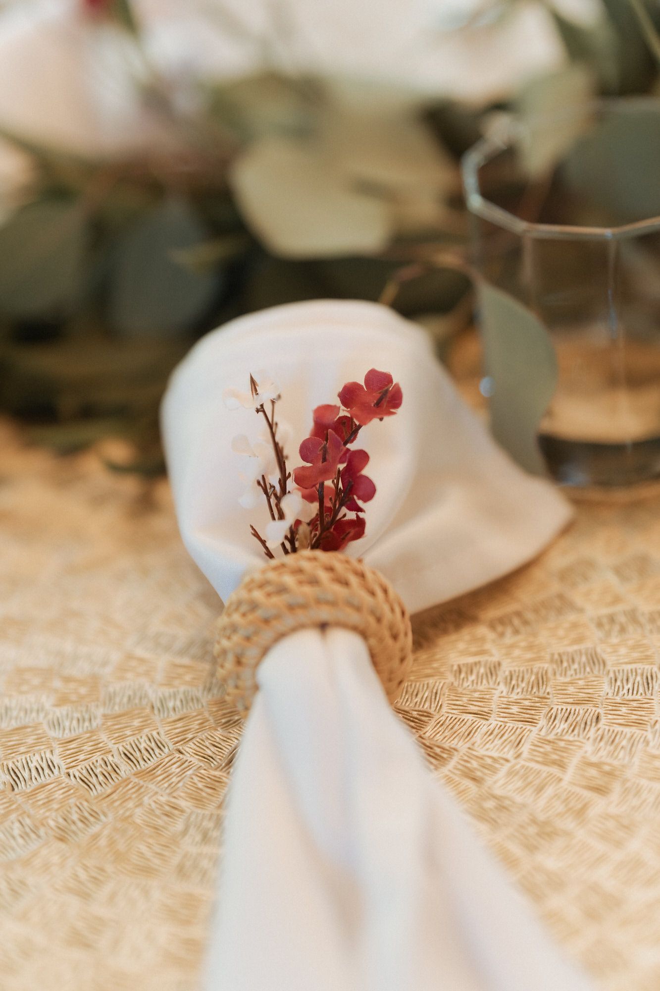 White lace tablecloth with delicate rose-colored floral decorations and elegant place settings in soft natural light.