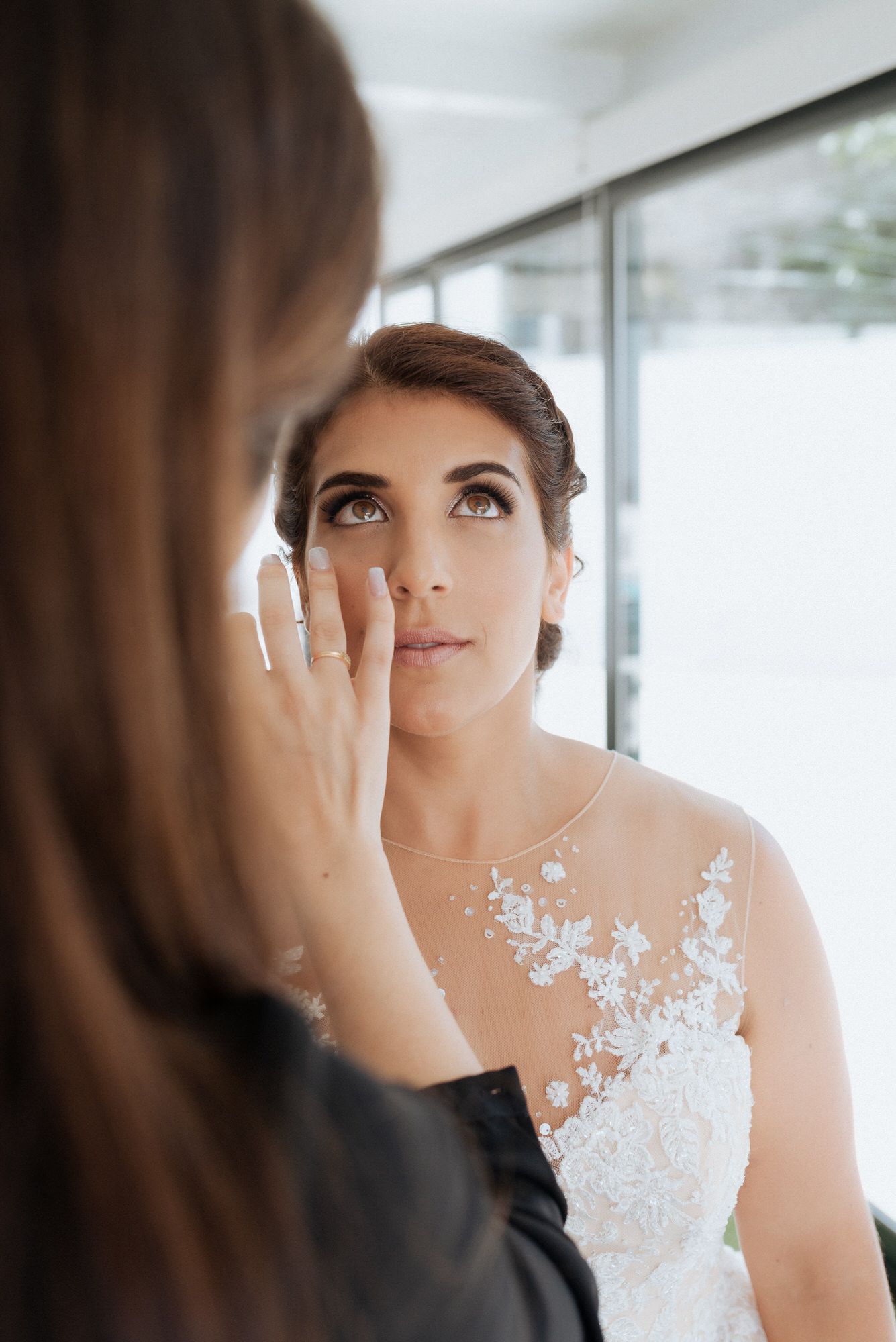 Close-up details of an elegant bridal gown featuring white floral lace appliques and sheer neckline.