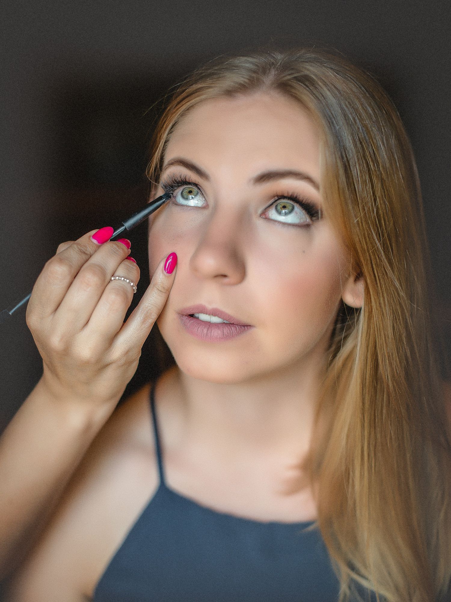 Close up da aplicação de maquiagem nos olhos com aplicador de rímel rosa. Preparação da noiva.