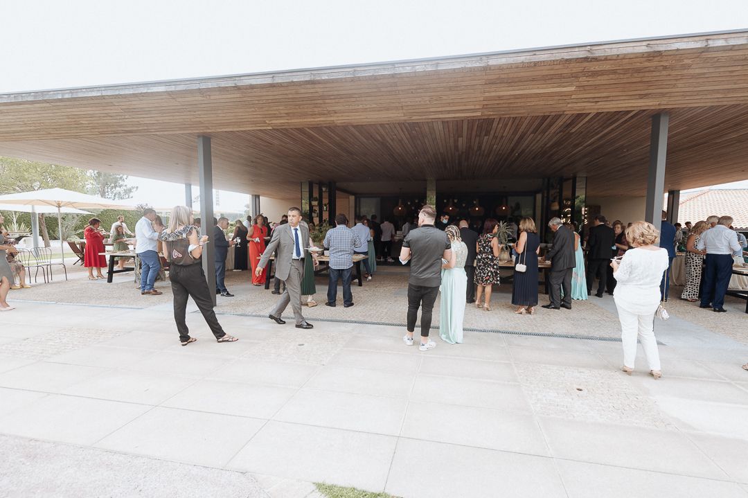 People gather under a covered outdoor venue area with tables and vendors during a community event.