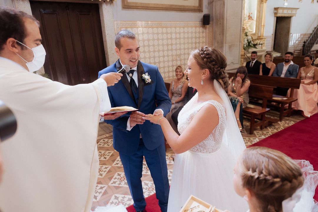A couple exchanges rings during their traditional church wedding ceremony while guests look on.