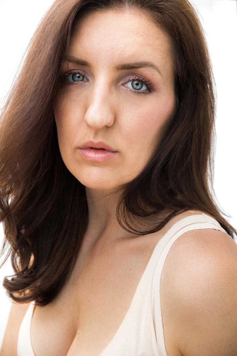 Close up beauty portrait with natural makeup wearing a white tank top against light background.