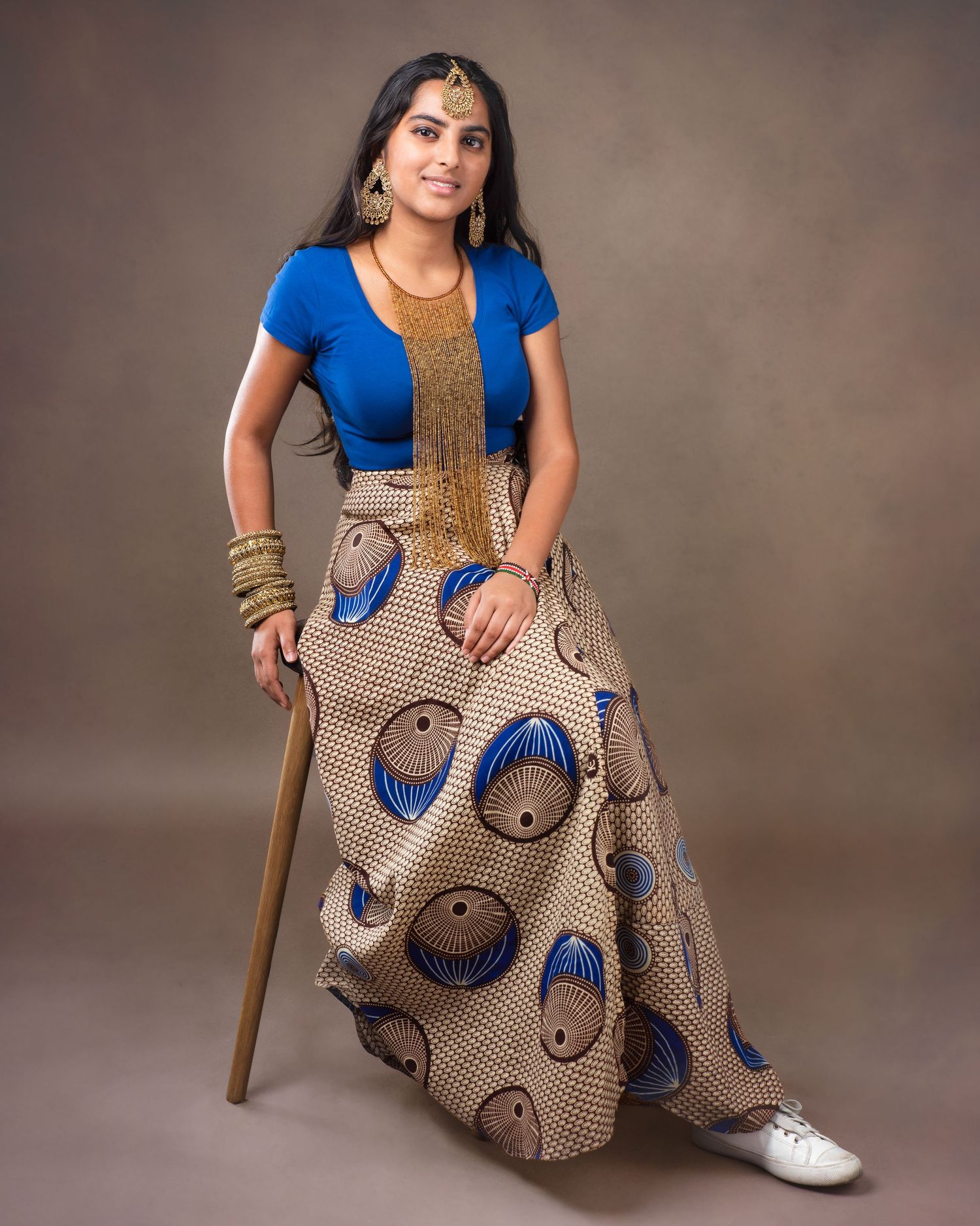 A row of 6 fashion photos featuring a model in a blue t-shirt and patterned maxi skirt posing on a brown backdrop.