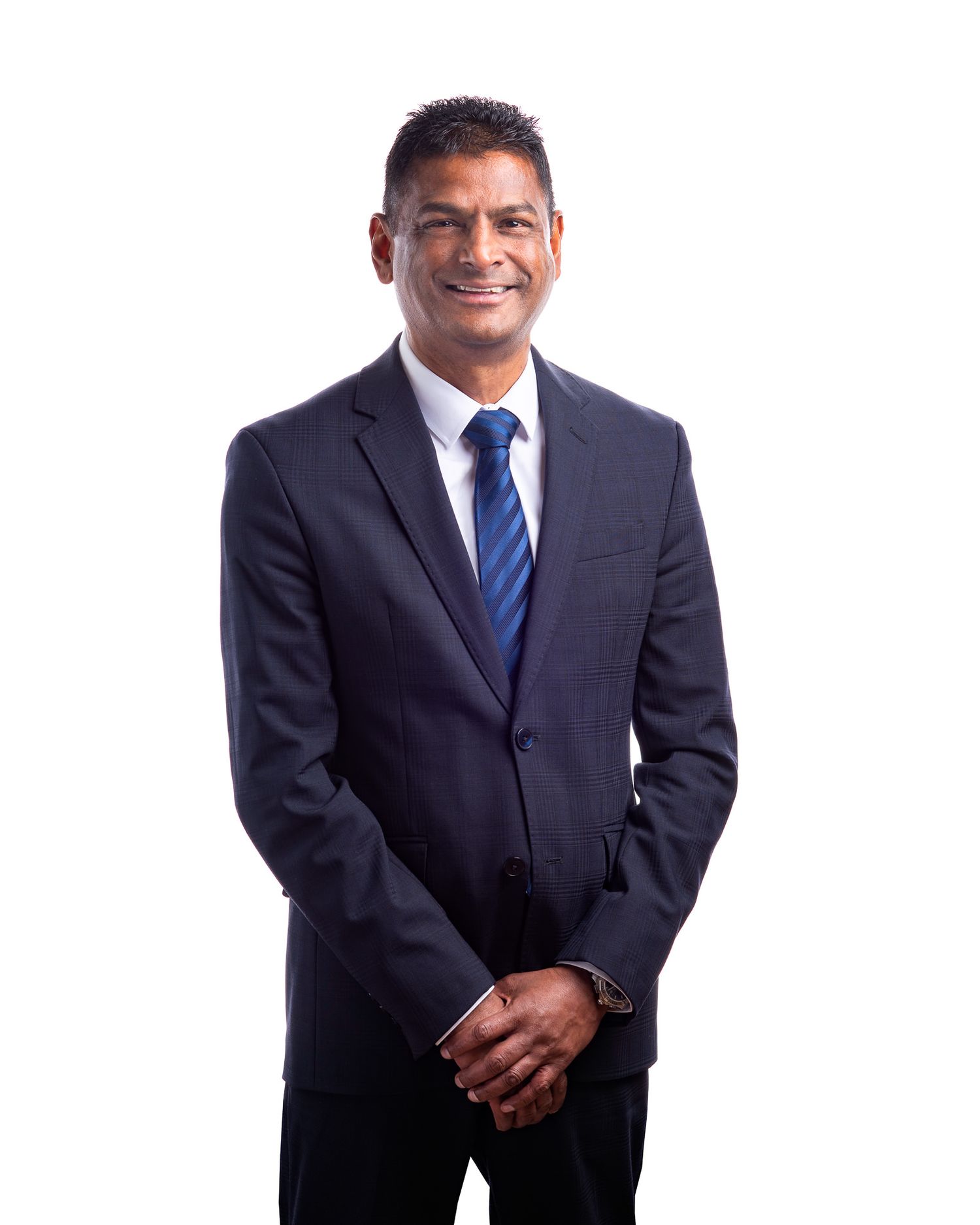 Professional wearing a navy suit and striped blue tie poses against white background.
